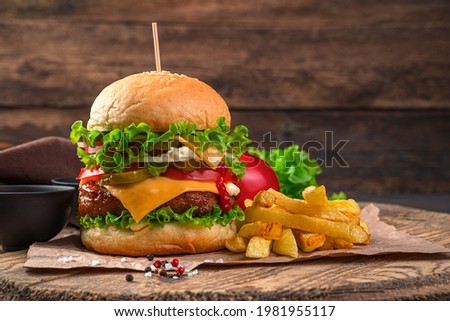 Burger with meat and French fries on a wooden background. Side view, copy space. Fast food.