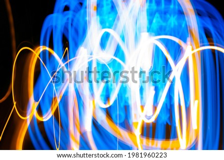 Blue and gold light painting, long exposure photography, abstract swirls and waves against a black background. Long exposure photo taken on a road