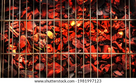 Red and hot pieces of coals or smolders under grill grate. Top view.