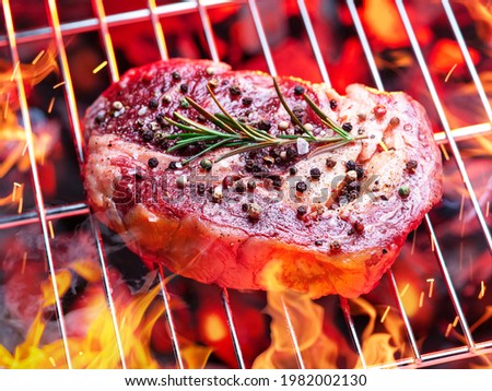 Roasted filet mignon beef steak on bbq grate over hot pieces of coals.