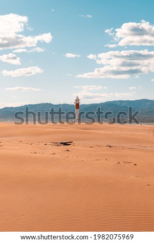 "Fangar" lighthouse situated in Ebro Delta beach. Picture taked during a sunny day with clouds in a blue sky.