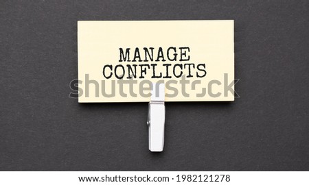MANAGE CONFLICTS text on paper with wihte clip. On black background