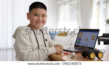 Young asia student remotely learn online at home in coding robot car and electronic board cable in STEM, STEAM, mathematics engineering science technology computer code in robotics for kids concept. Royalty-Free Stock Photo #1982180873