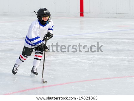 A young hockey player races with the puck. Royalty-Free Stock Photo #19821865