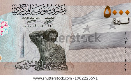 a soldier centred and saluting the flag of the Syrian Arab Republic. Portrait from Syrian 5000 Pound 2021 Banknotes.