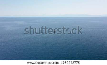 Incredible aerial shot in the open sea with a view of a white boat sailing in Aegean Sea, Greece.