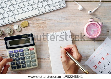 Wooden work table with laptop keyboard Coin money calculator clock calendar and supplies. cost concept.