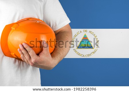 Worker with Nicaragua flag on background for working on labor day. Construction concept.
