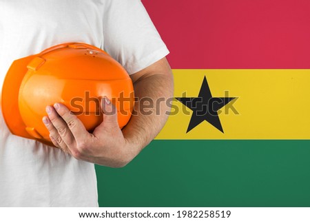 Worker with Ghana flag on background for working on labor day. Construction concept.