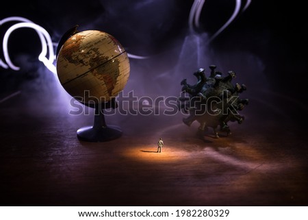 Corona virus global pandemic concept. Miniature man standing near big Corona virus novel in dark. Creative decoration with fog and backlight. Selective focus