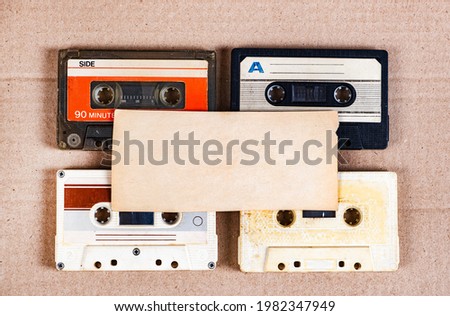 Four Old Audio Cassettes and Empty Paper on the Cardboard Background closeup