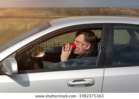 The manager eats lunch at the wheel in the car.