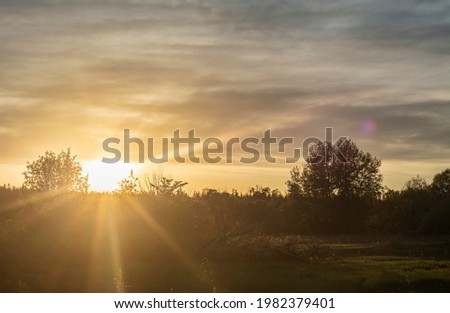 sun rises sets over green field and forest