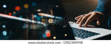 young man hand working on a laptop, bokeh blurred at night For text copy space, image size horizontal Royalty-Free Stock Photo #1982384948