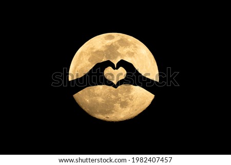 Love and moon.
Silhouette heart of hand on full moon background , hand of love.