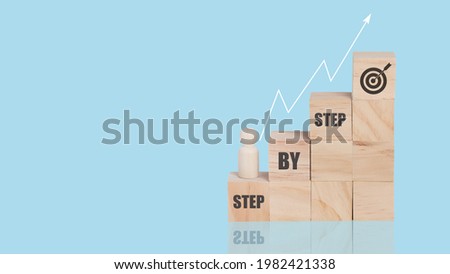 Wooden block stacking as step stair on top with word Step By Step with wood person model standing. Business target growth concept. isolated blue background. copy space.