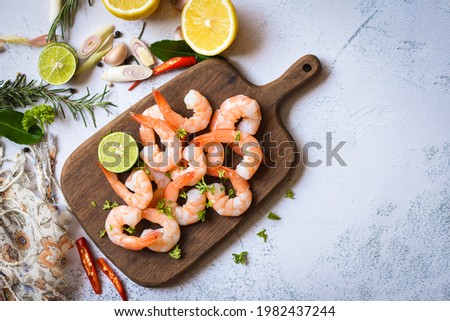 Shrimp peeled on wooden cutting board background on the table food kitchen, Fresh shrimps prawns seafood lemon lime with herbs and spice Royalty-Free Stock Photo #1982437244