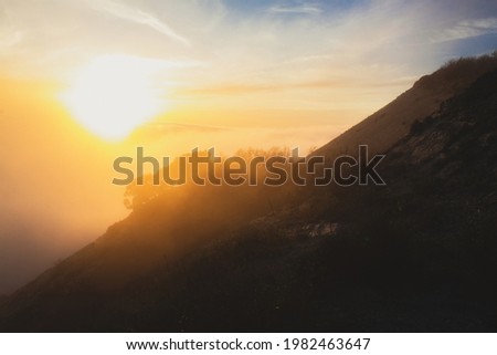 Traveler man is walking on hills among clouds. Beautiful Sunset on High mountains. Human inside Nature on blue sky background.
