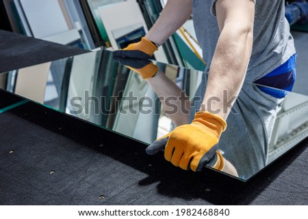 the glazier takes a piece of mirror off the table. Glass factory, manufacture  Royalty-Free Stock Photo #1982468840