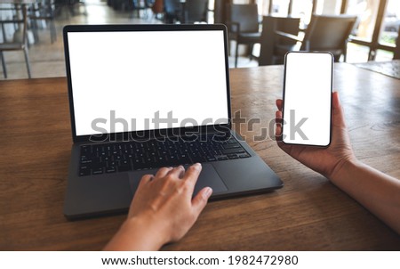 Mockup image of a woman touching on laptop touchpad with blank white desktop screen while using mobile phone