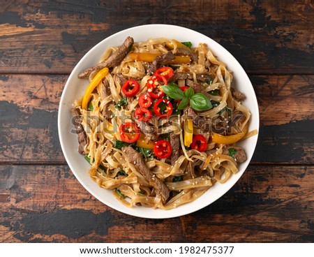Stir fry Beef Chow Fun with rice noodles, bean sprouts, spring onions and chili Royalty-Free Stock Photo #1982475377