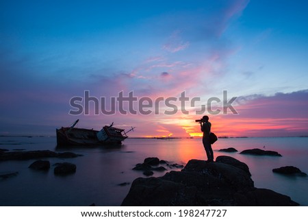 silhouette of a photographer who shoots a sunset in the sea