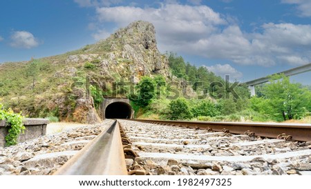 railroad track leading to a tunnel through a mountain