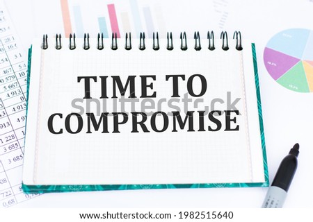 text TIME TO COMPROMISE written on notepad against the background of colored graphs. Business concept