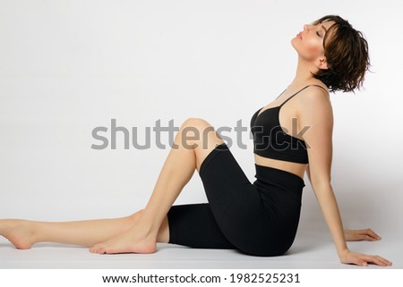 Short haired Woman on a white background sitting with a bra and spandex. Royalty-Free Stock Photo #1982525231