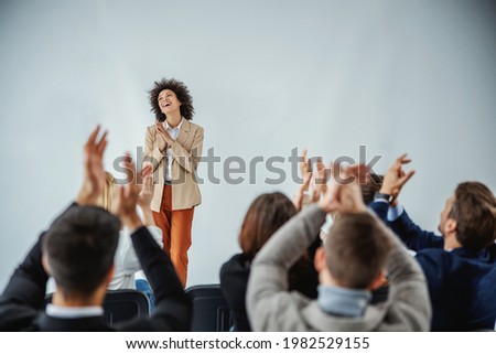 Successfully completed presentation. A multicultural group of businesspeople cheering and applauding a curly mixed-race entrepreneur who has just finished her speech on stage Royalty-Free Stock Photo #1982529155