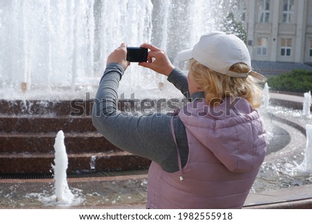 The girl takes pictures of the city fountain. St. Veronica's Day Photographer's Day .