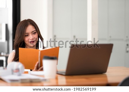 Attractive asian woman working with laptop computer during reading lecture on notebook at home