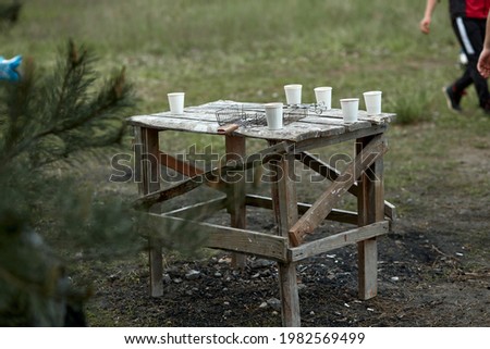 Disposable white glasses mockups on an old wooden table outside. Leisure activity concept. High quality photo