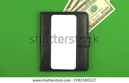 Mobile phone mockup screen with background of black leather and money on a green office table, business and finance application concept and template 
