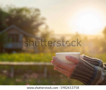 social distancing concept picture of hands holding a cup of coffee while having morning coffee far away from the people for safety. 