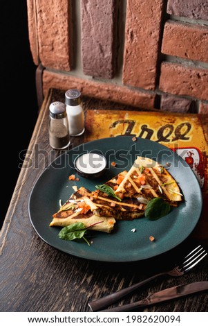Tortilla wrap with chicken and tomatoes on a dark green plate in a pub