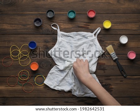 A woman twists a white T shirt for coloring in the style of tie dye. Staining fabric in tie dye style.