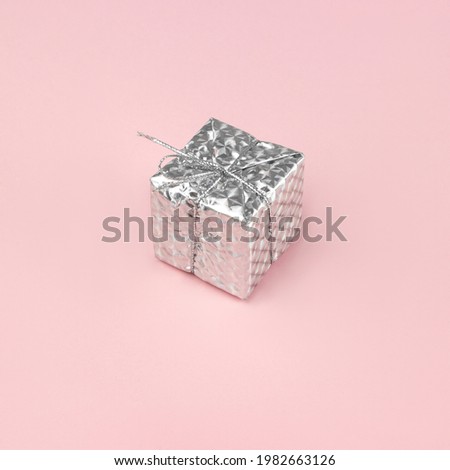Silver gift box over pink background. For christmas, new year and valentine concept. copy space.