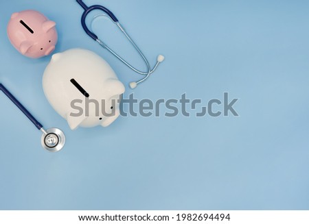 Top view of piggy bank with stethoscope isolated on light blue background with copy space. Health care financial checkup or saving for medical insurance costs concept.