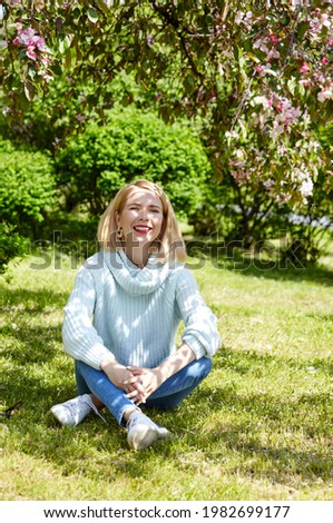 Woman on nature walk at spring park. Portrait photo of happy Caucasian woman in common clothes relaxing in outdoors park and have a good time on weekend activity