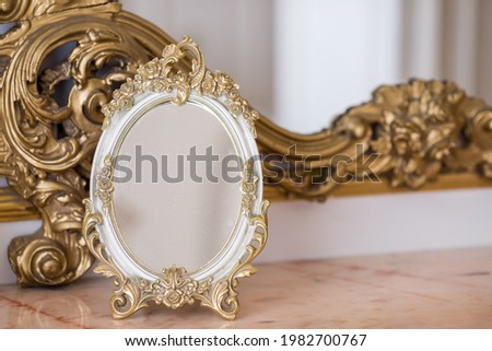 Antique oval mirror in gold frame in an old luxury interior close-up.
