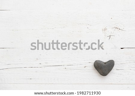 Stone heart decoration on a retro wooden table. Background for postcards with space for text. Festive season and celebration concept.