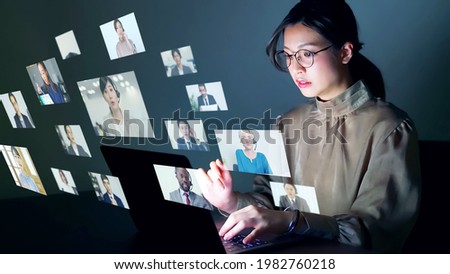 Young asian woman watching vlog screens. Telemeeting. Webinar. Distributor.  Royalty-Free Stock Photo #1982760218
