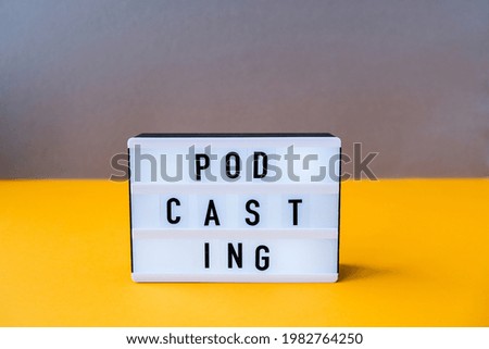 Lightbox with text podcasting in minimalistic isometric style. Trendy colors. Grey and yellow. New technologies. Millenial. Blogger, podcaster. Podcasting lettering. Audiobooks.