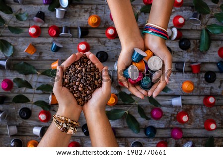 Coffee beans roasted, instant and grinded coffee in the mugs and coffee capsules in the hands of two woman. Many types of coffee on the wooden table.  Royalty-Free Stock Photo #1982770661
