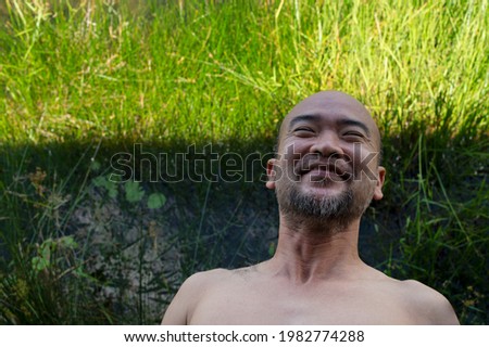 Asian Japanese 40s bald beard man with bright green plant outdoor nature background