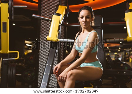 Muscular athletic woman resting after workout at gym and posing. Fitness female taking break after training session in health club. Healthy lifestyle fitness concept