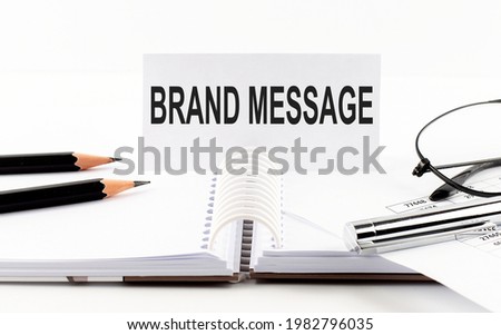 Text BRAND MESSAGE on paper card,pen, pencils, glasses,financial documentation on the table - business concept