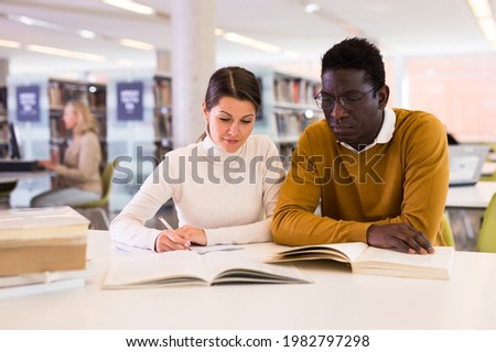 Portrait of couple of adult students studying together in public library. High quality photo