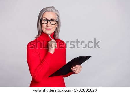 Photo of senior woman boss serious think pen touch chin clipboard isolated over grey color background Royalty-Free Stock Photo #1982801828